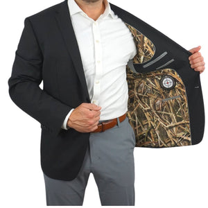 A person wearing a black blazer with the interior Mossy Oak Shadow Grass Blades liner visible.